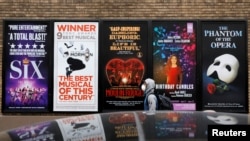 紐約曼哈頓百老匯劇院區的廣告旁走過一名戴著口罩的男子。 （2020年3月12日）