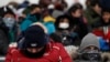 Spectators, with their faces covered, waiting for the start of the women's slopestyle qualifications at Phoenix Snow Park at the 2018 Winter Olympics in Pyeongchang, South Korea, Feb. 11, 2018.