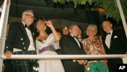 1987年5月29日，在福布斯杂志创刊70周年纪念活动中，出版家福布斯(左)，电影明星伊丽莎白·泰勒(左二)，大卫·洛克菲勒(右一)在帐篷里。(资料照片)