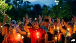 巴吞鲁日治愈之地大教堂前，为遇害警官举行烛光守夜仪式上，人们举起手进行祷告。（星期一，2016年7月18日）