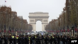 2018年12月15日，在法国巴黎的香榭丽舍大街，防暴警察站在身穿黄色马甲的抗议者面前，这些抗议者抗议高税收导致的生活成本上涨。（法新社）