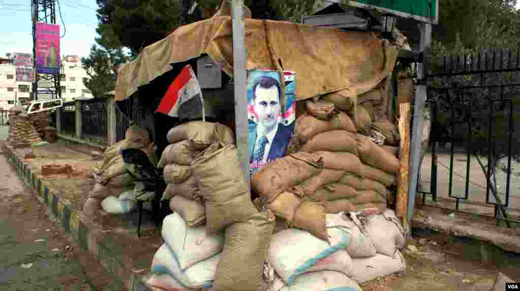 Hunkering down: a poster of Syria's president at a checkpoint on the outskirts of Damascus, January 2012. (E. Arrott/VOA)