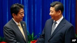 中國國家主席習近平（右）和日本首相安培晉三（左）去年在亞太經合組織會議上握手。