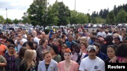 2014年6月10日，美國俄勒岡州波特蘭市附近的雷諾高中發生槍擊案。家長在警戒線後面等待承載著學生的校車的到來 