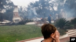 加州范杜拉市一名妇女在被烧毁的家前掩面哭泣。（2017年12月5日）