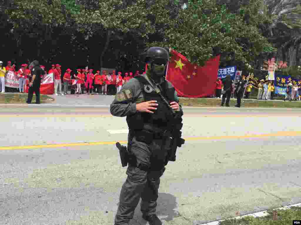 防爆警察與聚集在習近平下塌酒店附近的人群(美國之音莉雅拍攝)。這張圖片中有穿紅色上衣的歡迎習近平的人群，有人稱他們為紅衫軍，也有法輪功示威者。