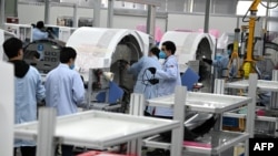 上海生產醫療設備的西門子工廠工人戴著口罩在生產線上工作。 （2020年2月24日）