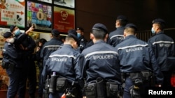 香港警察在逮捕《立場新聞》六名高管後站在該港媒辦公樓外。（2021年12月19日）