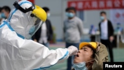 武汉一位医护人员正在对一名建筑工人提取进行核酸检测的样本。