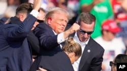 安全人员帮助前总统特朗普离开发生枪击事件的竞选集会现场。(2024年7月13日)