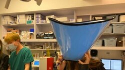 獸醫護士示範寵物主人都可以戴上頭套，避免與寵物太親密接觸。(美國之音湯惠芸)