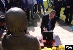 谢安达在慰安妇铜像和照片前拈香（美国之音记者国符拍摄）