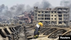 8月14日一名消防員站在損毀的汽車前。