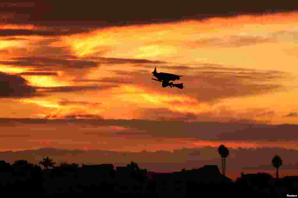 难道真有传说中的女巫骑着扫帚飞过？那是一架&ldquo;女巫骑扫帚&rdquo;形状的遥控飞机在落日的余晖中飞翔。这是在美国加利福尼亚州圣迭戈县下属的城镇恩西尼塔斯（ Encinitas ），时值万圣节，夕阳下，暮色中（2017年10月31日）。