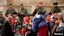 敘利亞政府軍戰士和俄羅斯士兵看著反叛武裝戰鬥人員及其家眷撤離霍姆斯市阿韋爾社區。 (2017年3月18日)
