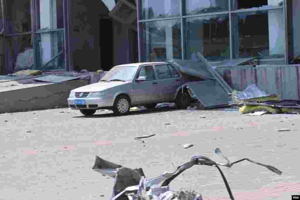 天津爆炸事故现场，核心爆炸区周围多座居民楼窗户被震碎，高速公路桥梁受损，多辆大货车被炸翻，小汽车起火或被砸，多名当地居民仍逗留在事故现场。（美国之音记者东方拍摄）