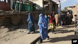 阿富汗妇女走向因地震被损坏的房屋（2015年10月26日）。