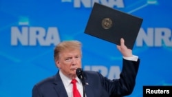 特朗普总统星期五在美国全国步枪协会讲话时手举停止批准武器贸易条约程序的政令。