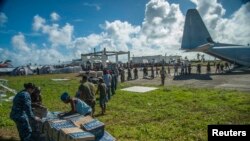 美军士兵和菲律宾民众11月17日在菲律宾灾区卸下救援物资。