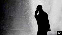 In this Oct. 11, 2012 file photo, a pedestrian talking on a cellphone is silhouetted in front of a fountain in Philadelphia.