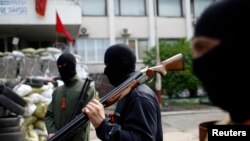 手持武器的親俄羅斯武裝分子在5月4日在東部港口城市馬里烏波爾市政廳前守衛。