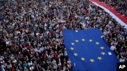 人群在华沙打出欧盟和波兰旗帜，抗议波兰保守派政府改造波兰法院。（2018年7月3日）