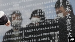 一名男子星期一在日本北部宮城縣石卷市大川區指著一名海嘯死難者的名字