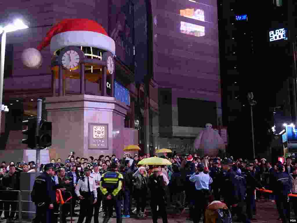 關上外牆電視屏幕及燈熄的銅鑼灣時代廣場，站滿平安夜報佳音及倒數的人群