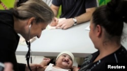 FILE - A doctor examines a baby with a cleft lip during a medical evaluation provided by Operation Smile volunteers at San Felipe hospital in Tegucigalpa, Honduras, Nov. 14, 2012.