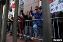 香港亲北京，反港独的示威者挑战那些争取民主的示威群众，举着标语牌：“民主骗子，吹捧自己”。两派之间有栅栏隔开（2017年1月1日）