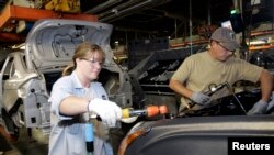 在密西根州一家福特汽车制造厂里，一名女工与男工人一起工作。