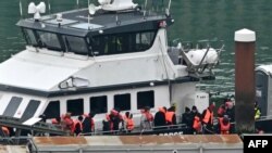 Wahamiaji waliochukuliwa baharini wakijaribu kuvuka Mfereji wa Kiingereza kutoka Ufaransa, wakishuka kutoka kwa meli ya Border Force 'Defender' baada ya kuwasili Marina huko Dover, kusini mashariki mwa Uingereza, Januari 17, 2024. 