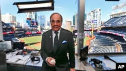 FILE - In this Sept. 29, 2016, file photo, Dick Enberg, the voice of the San Diego Padres, poses in his booth prior to the Padres' final home baseball game of the season in San Diego.