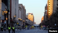 2013年4月16日，两名警察走在波士顿马拉松爆炸案现场附近的街道上。