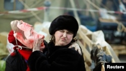 在基辅独立广场，一位支持与欧盟融合的反政府示威者带着丑化俄罗斯总统普京的面具试图亲吻一名女士。（2013年12月22日）