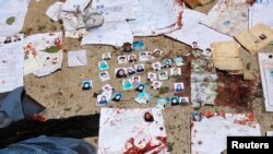 阿富汗喀布爾一個選民注冊站外遭襲擊後地面上散落的身份證和照片。（2018年4月22日）