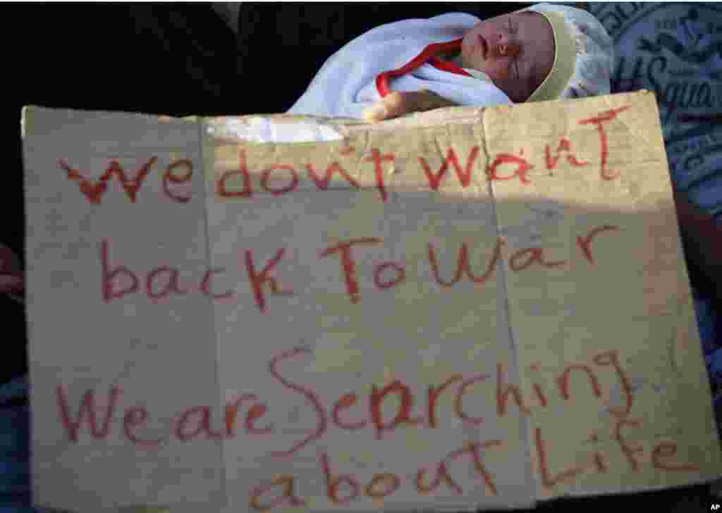 A man show a placard as migrants, mostly Syrians, trying to reach Europe rest outside the Turkish city of Edirne, which borders European Union members Greece and Bulgaria, Sept. 16, 2015.