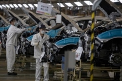 工人们佩戴口罩在位于湖北省武汉市的汽车装配线上工作。（2020年4月8日）