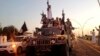 FILE - Fighters from the Islamic State group parade in a commandeered Iraqi security forces armored vehicle down a main road at the northern city of Mosul, Iraq.