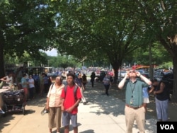 在首都史密森尼航空航天博物馆旁边观看日食的游人。(2017年8月21日)