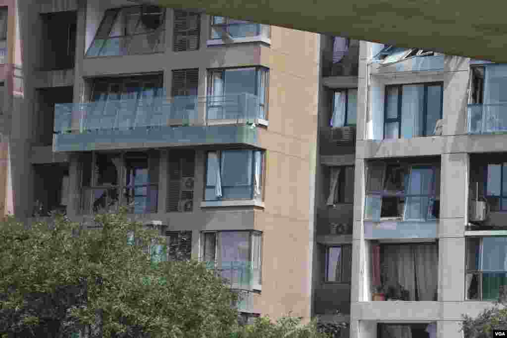 天津爆炸事故现场，核心爆炸区周围多座居民楼窗户被震碎，高速公路桥梁受损，多辆大货车被炸翻，小汽车起火或被砸，多名当地居民仍逗留在事故现场。（美国之音记者东方拍摄）