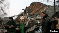 联合国一份新的报告说，乌克兰东部等地区的地缘政治动荡因素可能会破坏全球经济增长。图为乌东一名亲俄分离武装分子和一位居民在顿涅茨克附近查看被炮击摧毁的房屋废墟。
