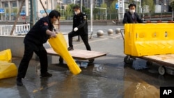 武汉市解除封锁，几名工作人员正在移除马路上的障碍物。（2020年4月7日）