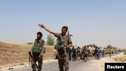 2016年8月10日，阿富汗国民军战士在抵达赫尔曼德省某区时在公路上打手势。