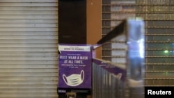 在 2022 年 1 月 9 日在香港採取更嚴格的限制措施以遏制新冠病毒的傳播之後，在空蕩蕩的蘭桂坊夜生活區的封閉酒吧外可以看到一張提醒人們戴防護口罩的海報 （路透社照片）