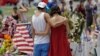 FILE - A couple spend a quiet moment at a makeshift memorial honoring the victims of the Pulse nightclub mass shooting, June 20, 2016, in Orlando, Fla.