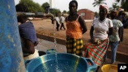 Girls fill plastic basins at a free water tap in a neighborhood where houses with indoor plumbing rarely receive water, in Bissau, Guinea-Bissau, March 6, 2009. Contaminated drinking water leads to yearly cholera epidemics, particularly in remote rural re
