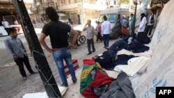  敘利亞人站在被桶裝炸彈炸死者的屍體旁（2015年5月30日）