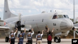 日本海上自卫队的一架飞机准备从澳大利亚皇家空军在珀斯的基地起飞，搜寻失踪的马航MH370班机，日本救灾队员在跑道挥手告别。（2014年3月24日）