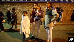 Residents stand outside their apartments in a street near the "Tower of David" skyscraper, which suffered an inclination after a powerful earthquake shook eastern Venezuela, causing buildings to be evacuated in the capital of Caracas, Aug. 21, 2018. 
